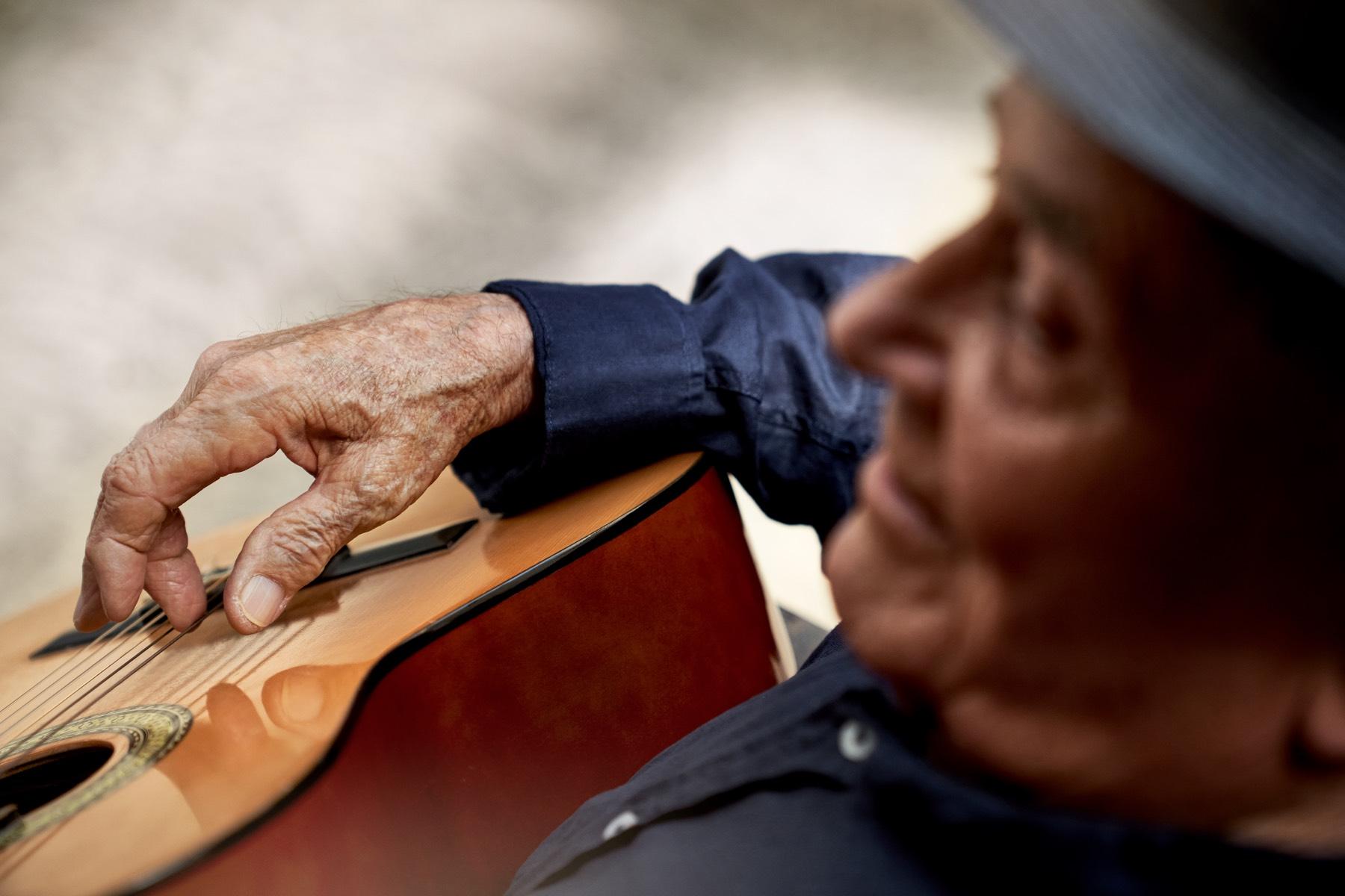 Oceania resident strumming a guitar