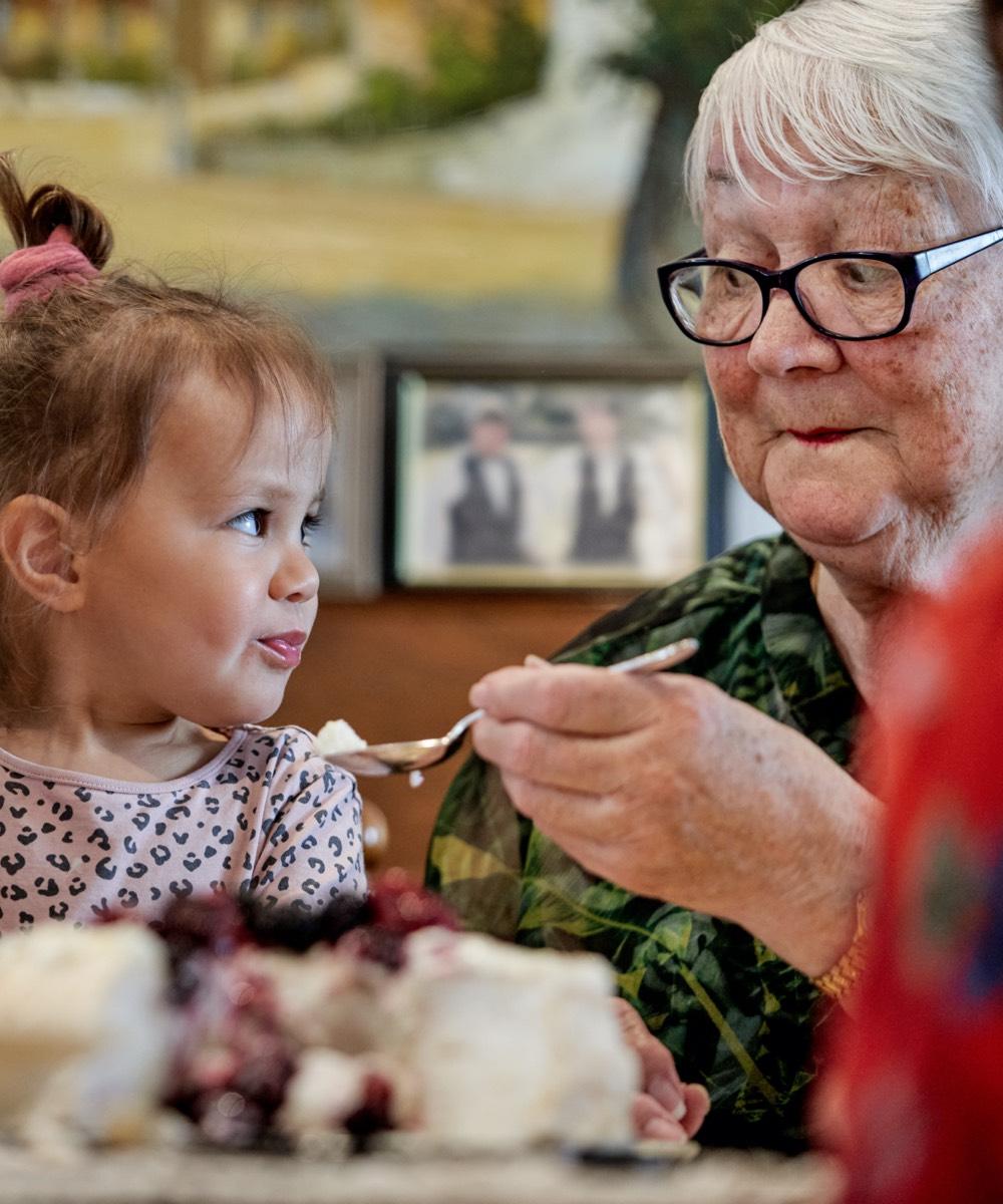 Oceania resident sharing dessert with young girl