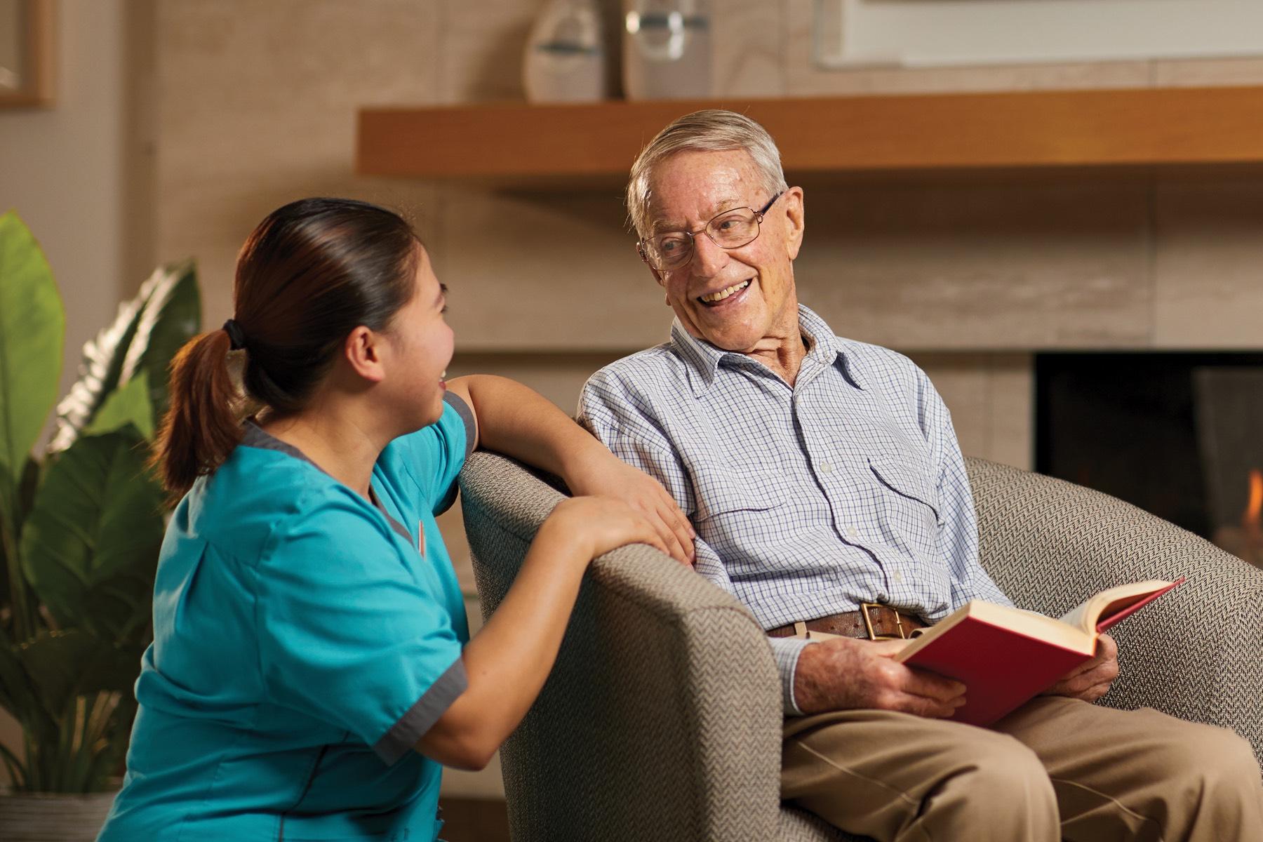Oceania resident reading with a healthcare assistant